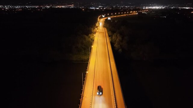 Aerial view of illuminated highway at night with vehicles traveling along the road, showcasing the vibrant city lights and surrounding landscape in the background. Auto riding at evening route way