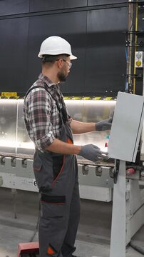 Industrial worker operating a factory machine control panel