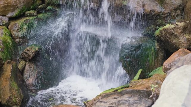 Powerful water flowing over mossy rocks at waterfall