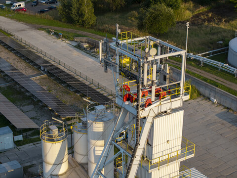 Aerial view of the Wieliczka Salt Mine shaft structure featuring industrial metal framework, red pulleys, storage tanks, and adjacent solar panels in Wieliczka, Lesser Poland Voivode, Poland.