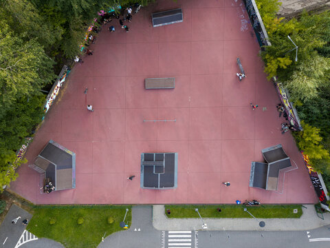 Aerial view of a skatepark with ramps, rails, and people skating on a red surface in Wieliczka, Lesser Poland Voivode, Poland.