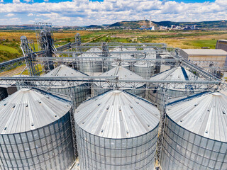 Grain storage silos located in a rural area under a blue sky with clouds © DSMT