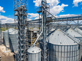 Large silos and storage structures at a grain handling facility under a bright blue sky with clouds © DSMT