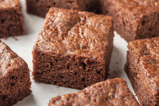 Chocolate zucchini brownie squares close up on white textured background