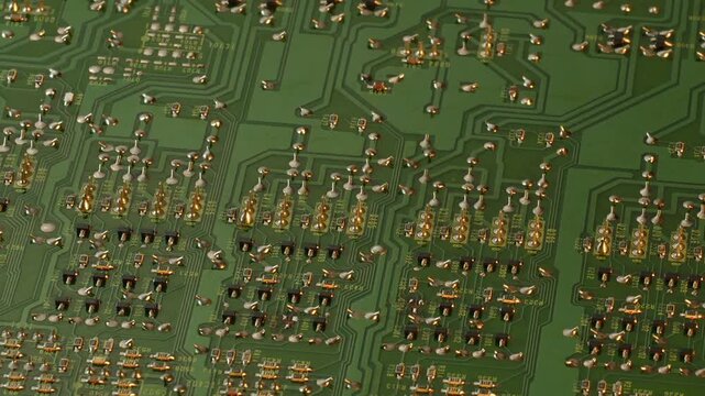 Rotating green printed circuit board with solder joints and component codes in macro view