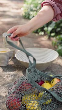 Picking Apples from a Basket on a Garden Table