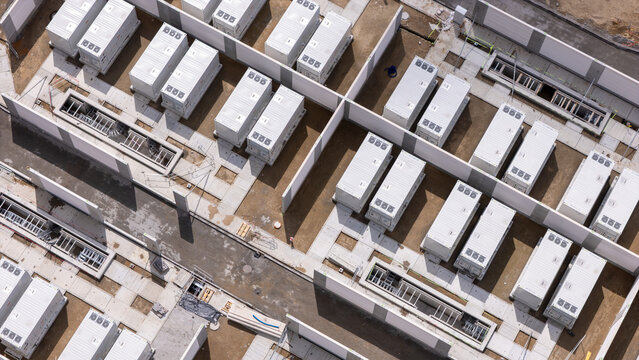 Aerial view of the Zarnowiec Pumped Storage Power Plant featuring rows of white containerized battery energy storage systems on concrete pads in Wejherowo County, Pomeranian Voivodeship, Poland.