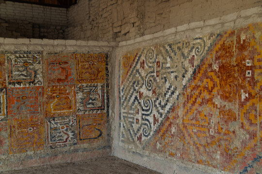 Ancient Moche polychrome murals with stylized animal figures and geometric patterns on an adobe wall corner at the Lady of Cao precinct in El Brujo, Peru