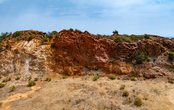 Aerial view of the iron-rich geological formations at the old iron mine area near Laghetto delle conche, with reddish-brown rock faces and sparse vegetation in Rio Marina, Toscana, Italy.