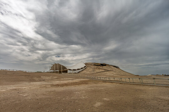 Panoramic view of the Huaca Cao Viejo mound protected by a large tensile canopy structure in the desert landscape at El Brujo, Peru