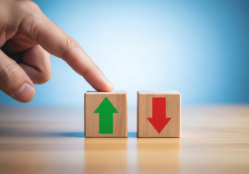 Hand touching wooden block with green arrow pointing up next to red arrow pointing down representing business growth versus decline concept.