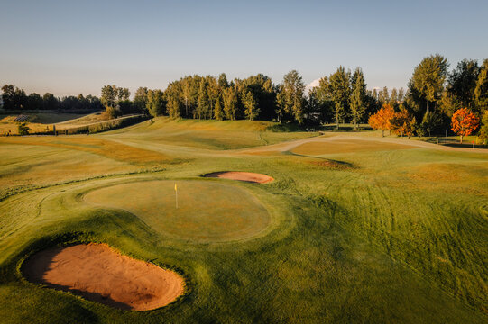 Aerial view of a golf course featuring green fairways, sand bunkers, and surrounding trees during golden hour in Valmiera, Valmiera, Latvija.