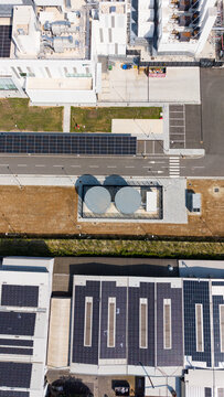 Aerial view of a modern hyperscale data center featuring large industrial buildings with extensive rooftop solar panel arrays, cooling tanks, and paved service areas, Melegnano, Lombardy, Italy.