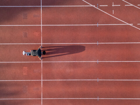 Aerial view of a runner in starting blocks on a red running track with white lane markings in Almere, Flevoland, Netherlands.