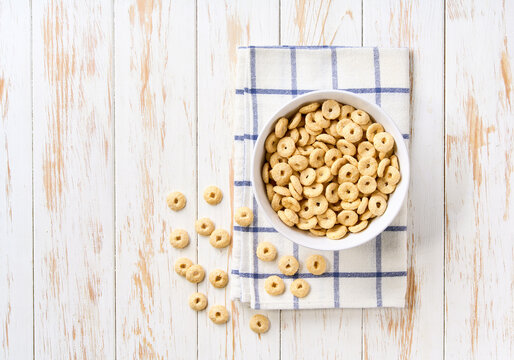 ceramic bowl of tasty corn rings on a light kitchen table, top view. Copy space for text.