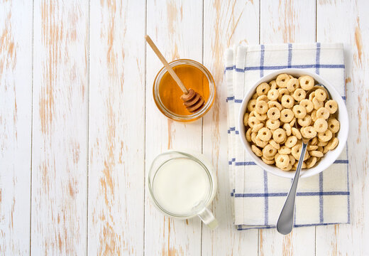 bowl of tasty corn rings with milk and honey on a light kitchen table.Top view. healthy sweet snack for breakfast.