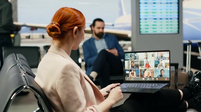 A businesswoman joins a video call briefing on a laptop in an airport lounge, discussing corporate issues with workers and shareholders while traveling.
