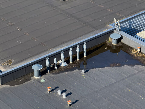 Aerial view of a flat roof featuring several ventilation pipes and areas of standing water in Leeuwarden, Friesland, Netherlands.