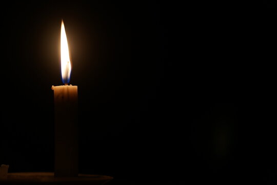 Single Burning Candle Flame in the Dark with Copy Space