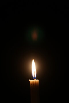 Glowing Candle Light against Black Background for Memorial, Hope, and Peace