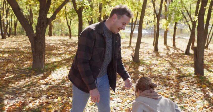 Father and daughter play in autumn giving high five. Family walk in a sunny park, laughing through golden leaves, sharing warm with child girl outdoors. Happy bonding, joy and leisure in nature.