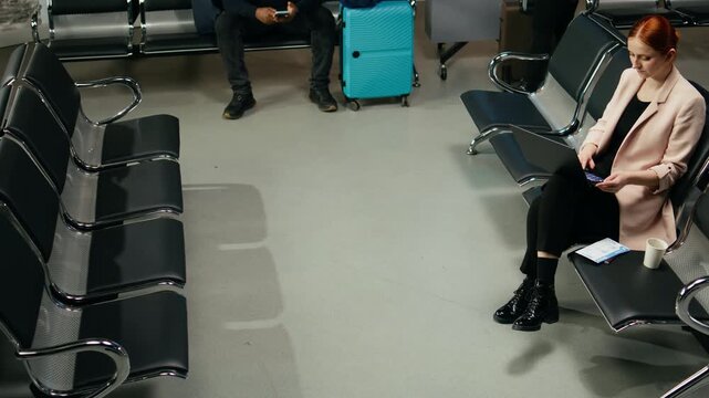 Businesswoman manages laptop tasks near an airport gate while preparing for an international flight and overseas work responsibilities abroad.