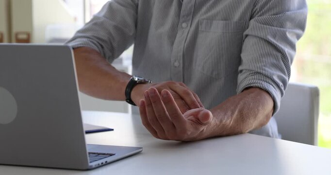 Man working and measuring his pulse at desk in office, closeup