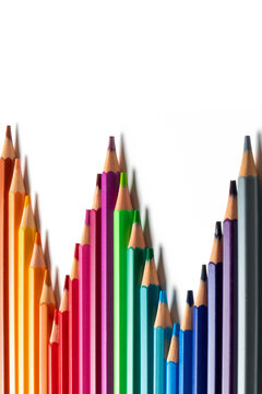 Colored pencils arranged in staggered lengths on a white background with copy space. Creates a bar chart concept symbolizing financial growth, business progress, creative statistics, art education.