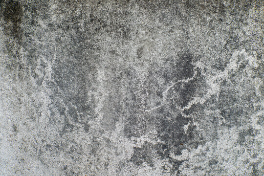 Weathered concrete wall texture featuring dark grunge patterns and rough surface details. Background overlay, digital design element, or distressed architectural backdrop