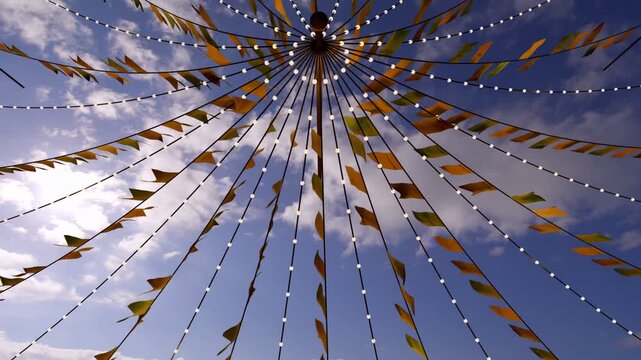 Central hub canopy lifting in gusting wind, pennants fluttering, creating yellow green patterns