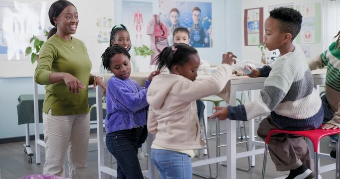 African American teacher guiding students at tall table passing bottle reaching wrappers recycling