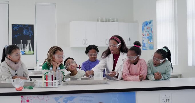 African American teacher with six goggled children pointing, pouring into tray teaching demo at lab
