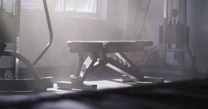 Shifting sunlight is moving dust and nudging workout bench forward near window, showing texture