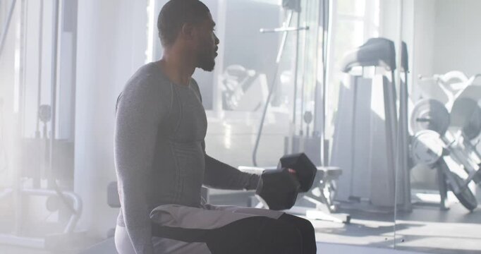 30s man starting right-arm curl on bench with dumbbells pausing adjusting posture for arms at gym