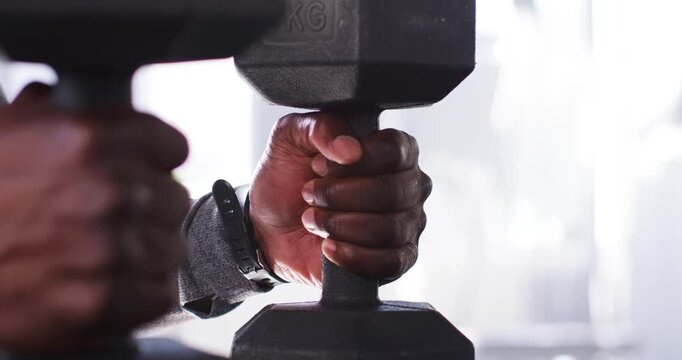 Man tightening and adjusting grip on 7KG dumbbell at gym, preparing for lift with wrist tracker