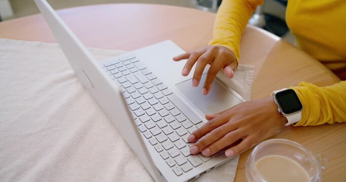 African American woman in yellow top placing hands on laptop typing using trackpad while working