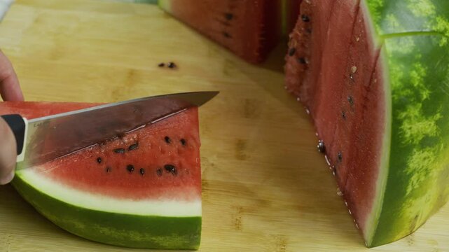 Closeup large knife cutting watermelon slices into triangles