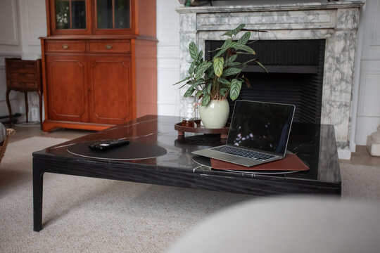 Open laptop on coffee table in cozy living room with fireplace
