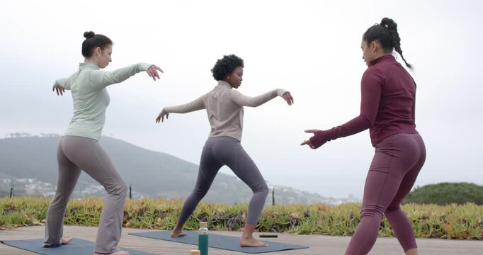 African American women practicing yoga, center leading cues, lunging on deck mats and phone