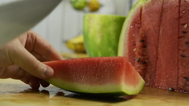 Slow motion closeup of knife cutting through watermelon slice