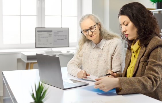 Senior client and advisor in office consultation. They review pension options on a laptop, discuss investments and retirement planning at a bright desk. Strong concept of retirement finance.
