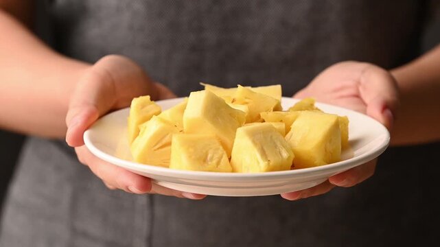 Close up of woman hands holding plate of sliced pineapple, Healthy eating