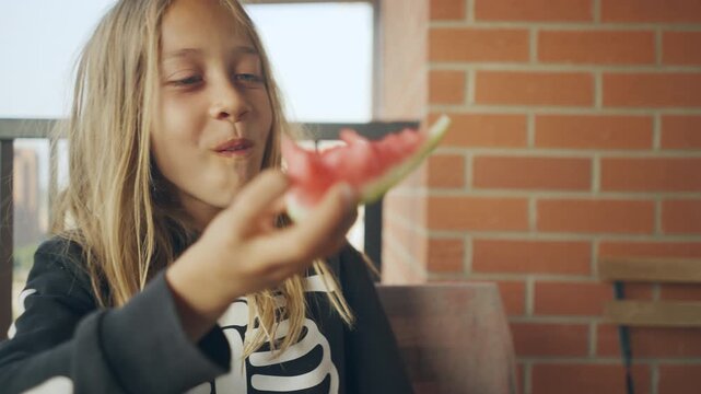 Close-up portrait of a child eating watermelon on a brick patio