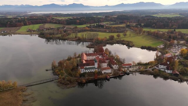Kloster Seeon liegt im Herzen des Chiemgau, umgeben von goldenen Herbstwaeldern und einem klaren See. Aerial panorama of Seeon Abbey in Upper Bavaria, Germany, with colorful autumn reflections.