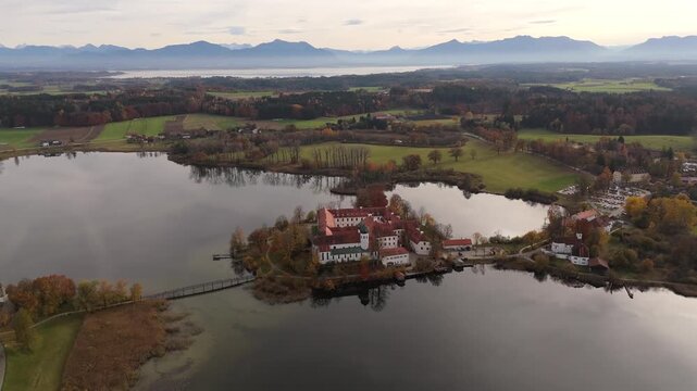Das historische Benediktinerkloster Seeon steht auf einer Halbinsel im Seeoner See, Oberbayern. Drone view shows the monastery island near the Bavarian Alps in warm autumn colors.