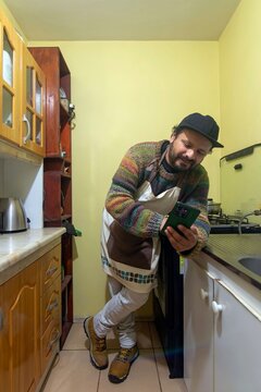 Man wearing a knitted sweater checking a recipe or message on his phone at home, vertical shot