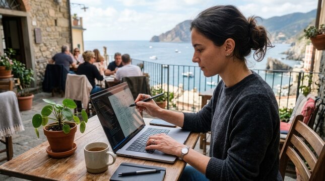 Young woman working remotely on laptop in a scenic coastal cafe, embracing digital nomad lifestyle