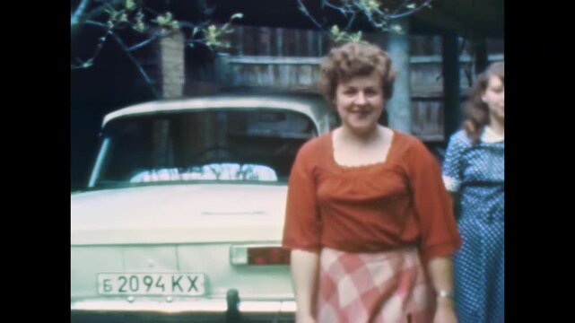 Smiling mother, adult daughter in elegant 1960s dresses together in sunny backyard. Warm family portrait. Nostalgic memories of everyday life. Old film. Archival retro. Vintage archive