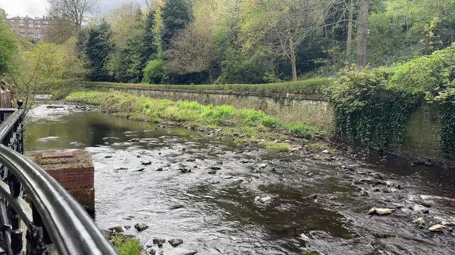 Static view of the Water of Leith flowing through Dean Village in Edinburgh, Scotland, featuring historic riverside buildings, lush greenery and a peaceful atmosphere.
