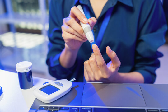Young Asian woman checking blood sugar level with glucose meter, diabetes monitoring and healthcare concept.